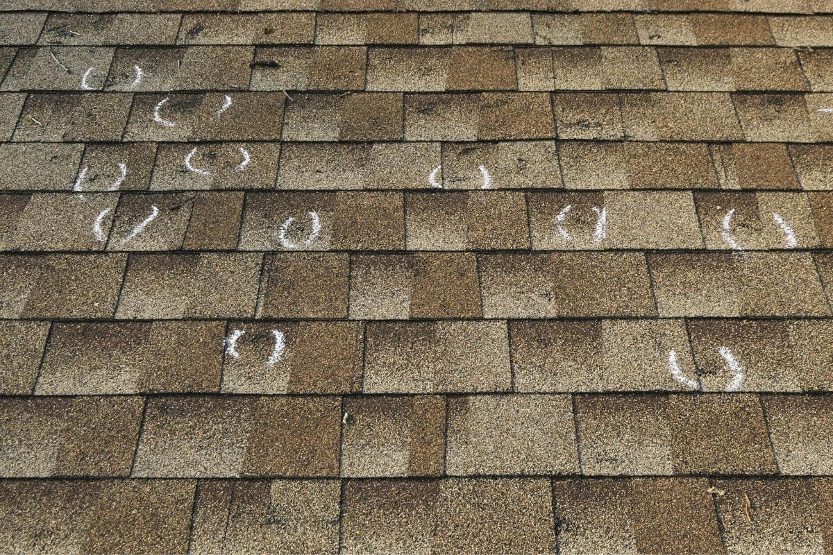 Midwest hail damage shingle bruising marked with chalk circles during inspection